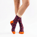 Person wearing blue socks with red pattern and orange toes on a white background
