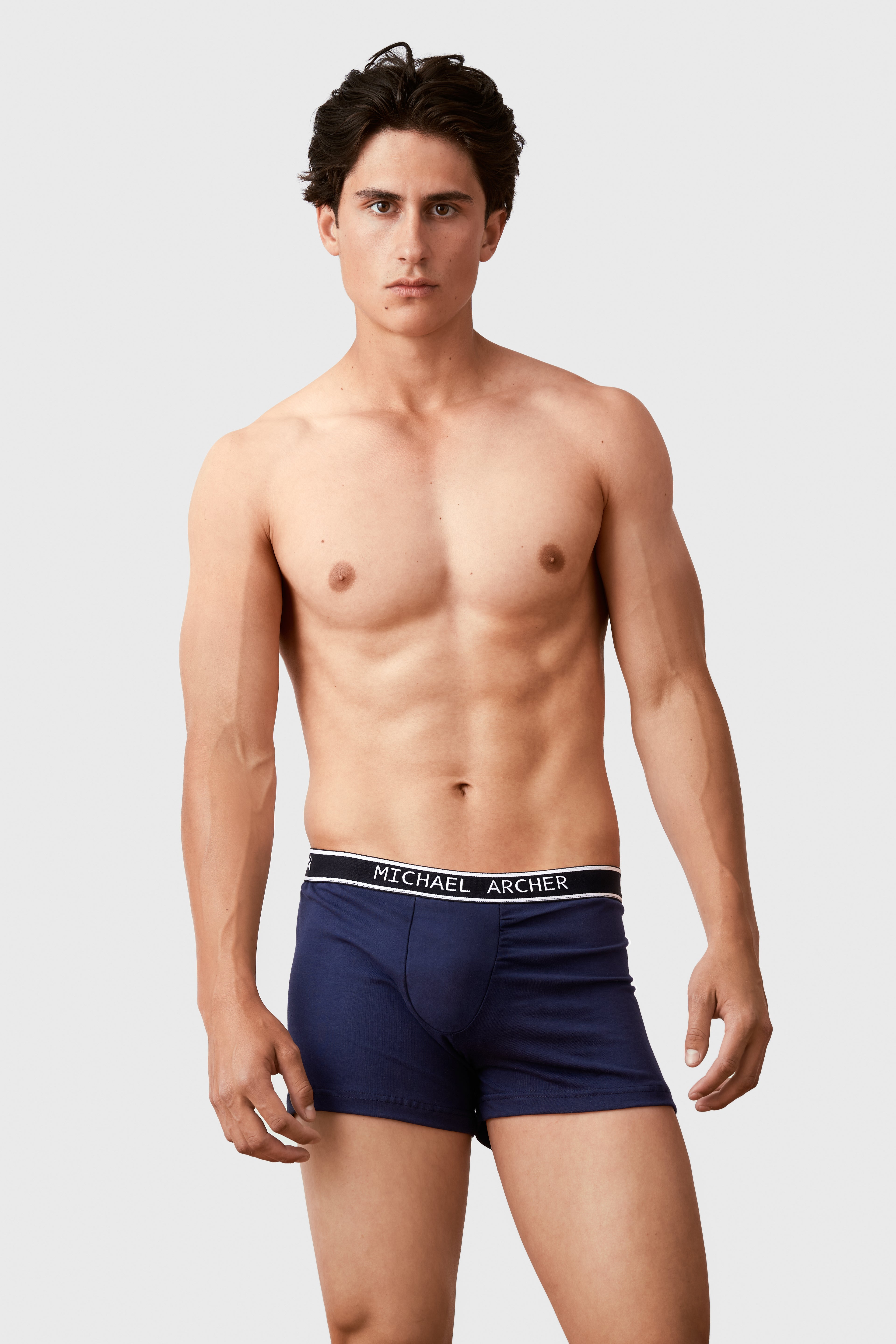 Man wearing navy blue boxer briefs with a visible brand label on a white background