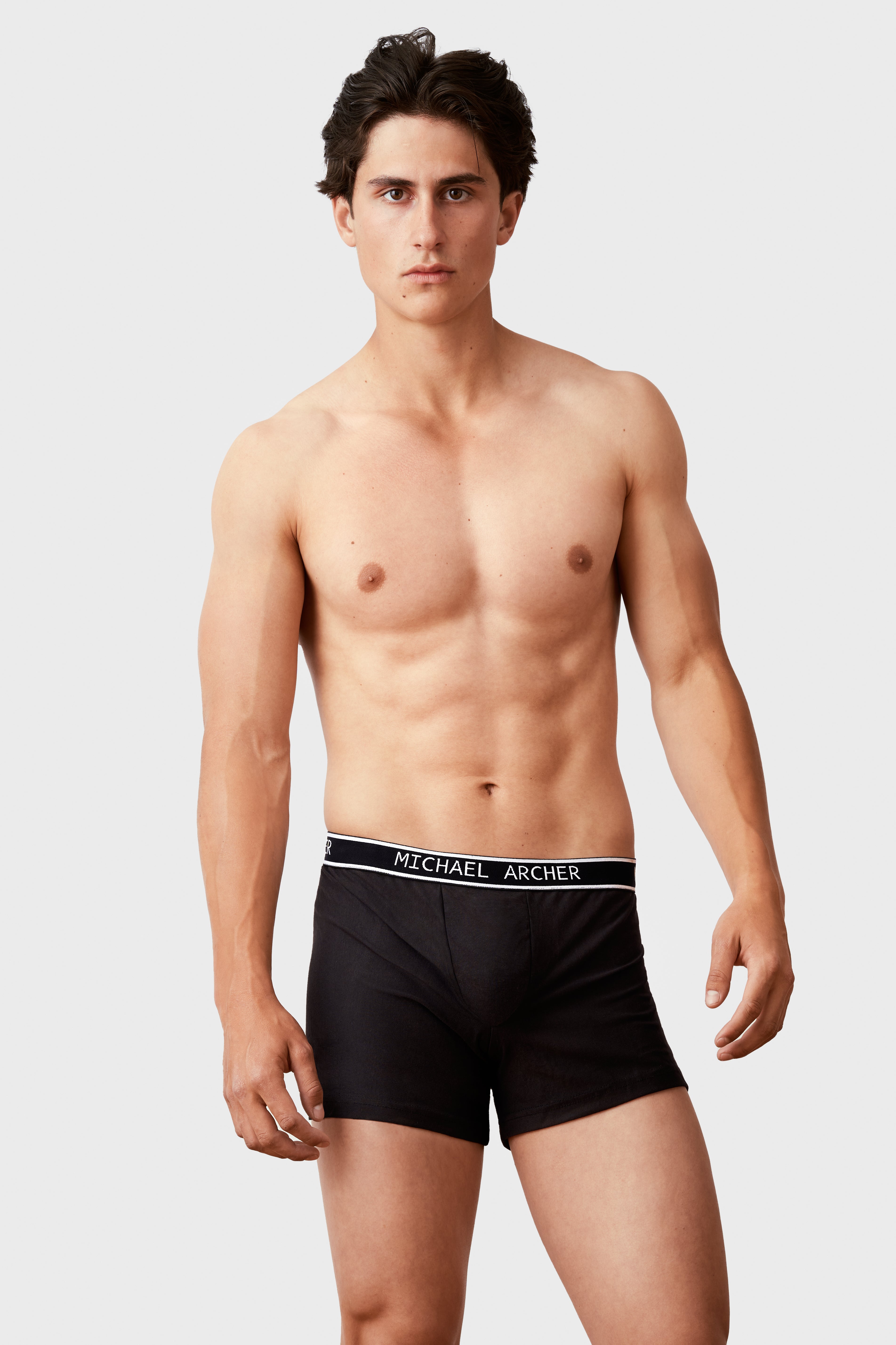Man wearing black boxer briefs with 'Michael Archer' branding on a white background