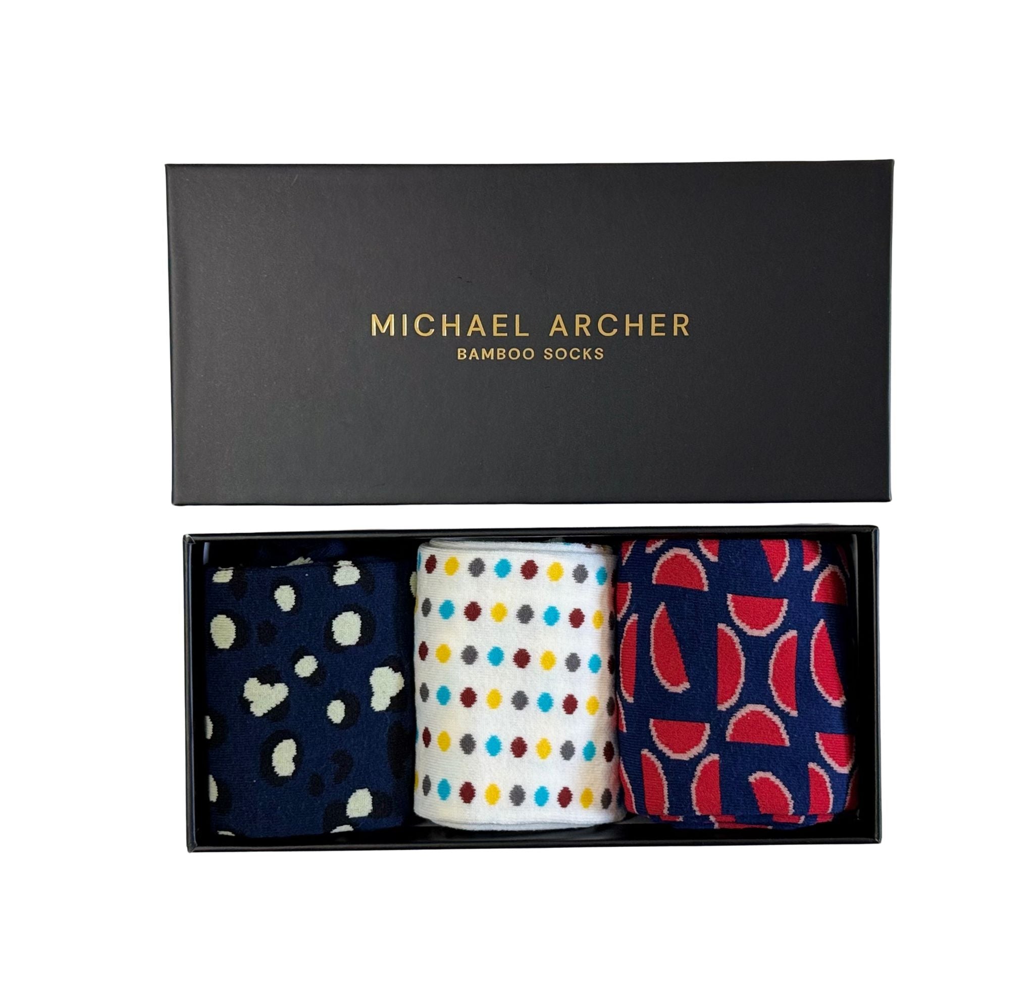 Three pairs of patterned socks in a black box with 'Michael Archer' branding.