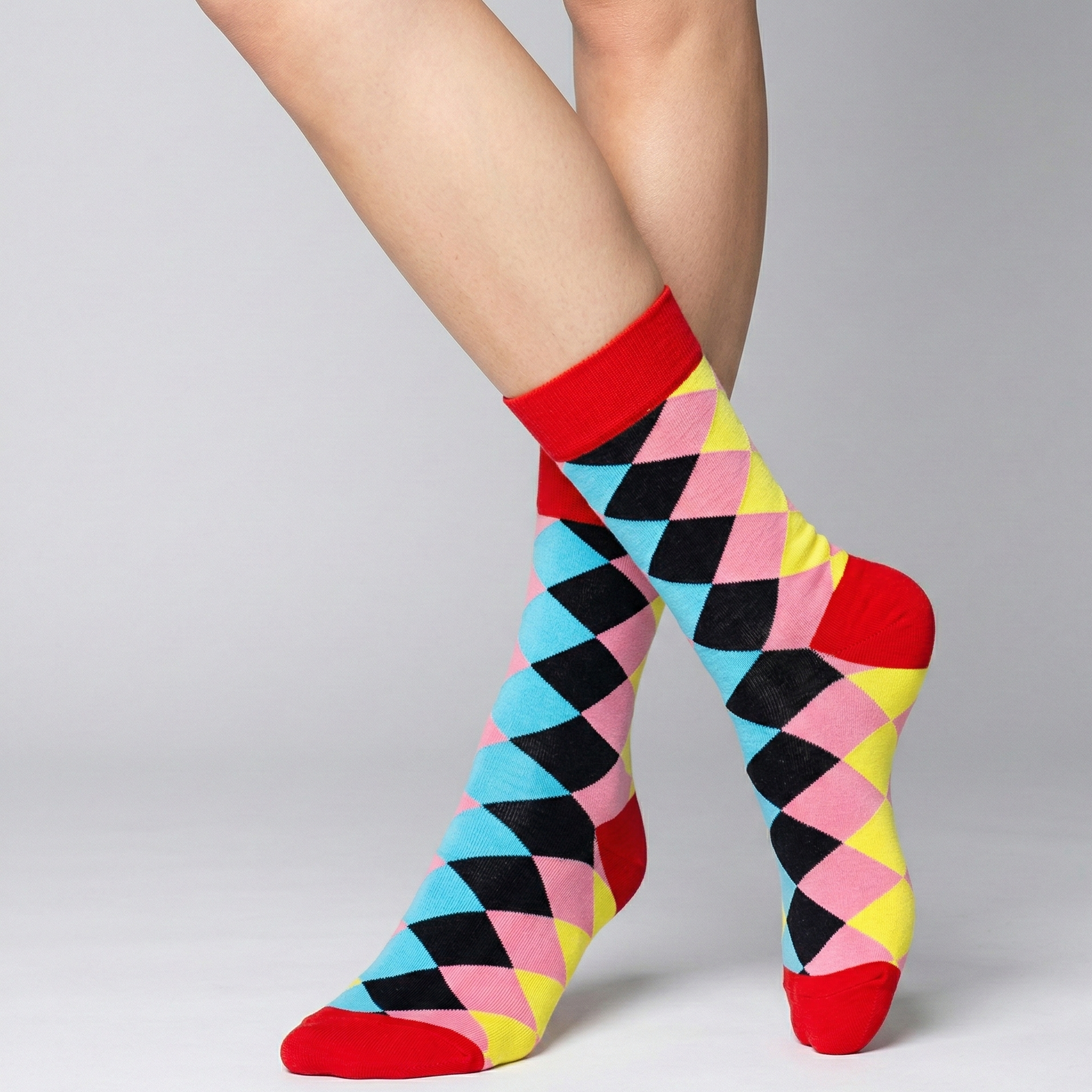 Colorful diamond-patterned socks worn by a person on a gray background