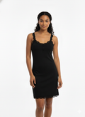 Woman wearing a black slip dress on a white background