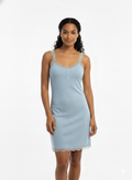 Woman wearing a light blue nightgown with lace trim on a white background