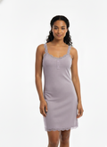 Woman wearing a light purple nightgown with lace trim on a white background