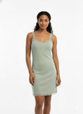 Woman wearing a light green nightgown against a white background